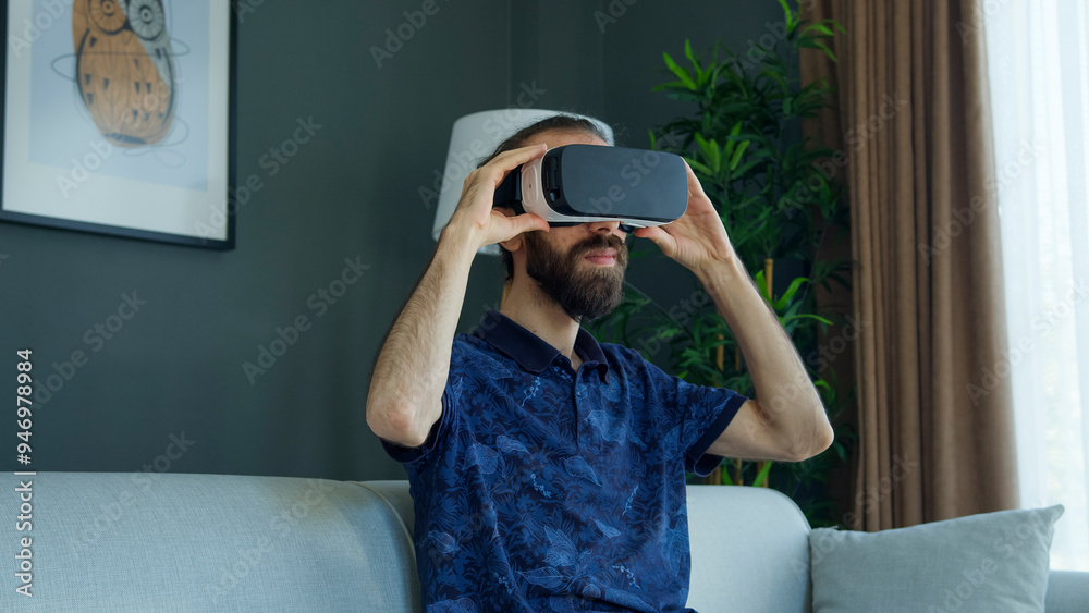 Fototapeta premium Bearded man wearing a VR headset explores virtual reality experience. Interacting with the virtual environment