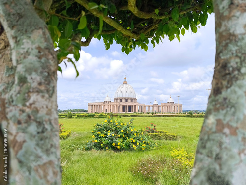 view of the Basilica of Our Lady of Peace of Yamoussoukro between the branches of a tree under a blue sky, Ivory Coast