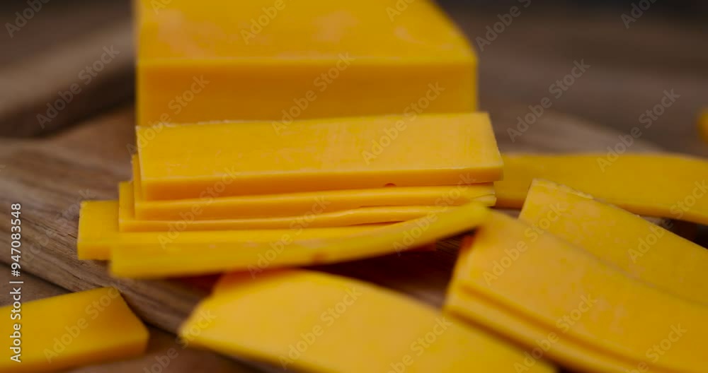 yellow hard cheese cut into long pieces, slicing yellow cheese close-up