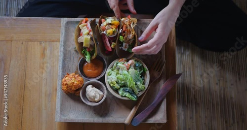 Top view of female hands taking taco in cozy vegan restaurant or cafe setting in Bali 