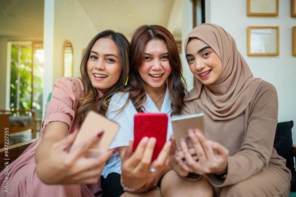 Three Indonesian women are sitting on a couch and video calls with their cell phones Three Indonesian women are sitting on a couch and video calls with their cell phones