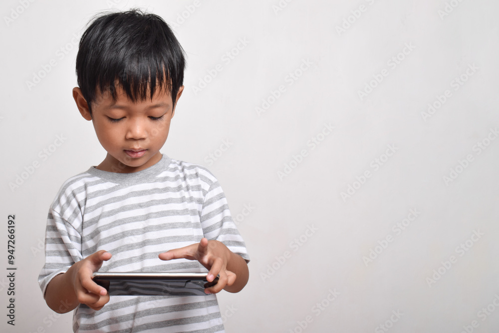 Asian boy with serious face playing smartphone isolated on white background. little boy addicted to playing games. Gaming and Technology concept, copy space Asian boy with serious face playing smartphone isolated on white background. little boy addicted to playing games. Gaming and Technology concept, copy space