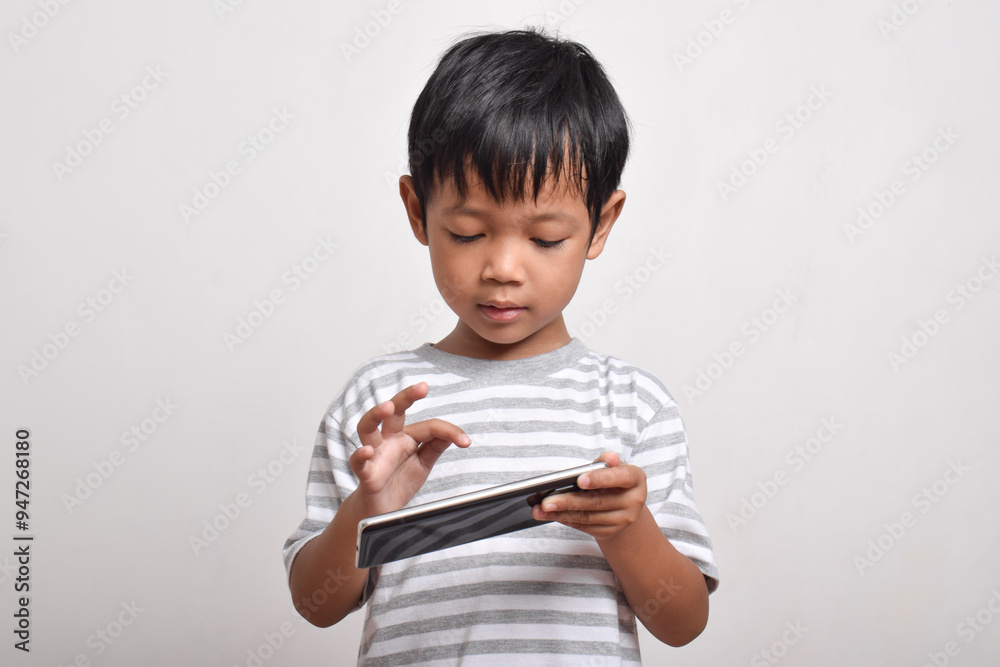 Asian boy with serious face playing smartphone isolated on white background. little boy addicted to playing games. Gaming and Technology concept, copy space Asian boy with serious face playing smartphone isolated on white background. little boy addicted to playing games. Gaming and Technology concept, copy space