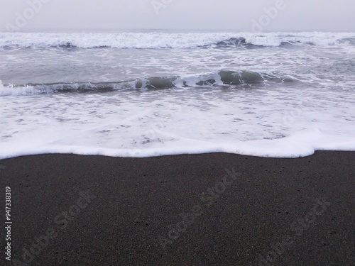 Crashing waves and black sand on Goa Cemara beach.