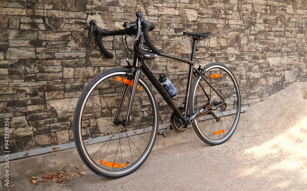 Racing bicycle leaning against stone wall. Road bike parked on sidewalk. Urban cycling and eco-friendly transportation concept.