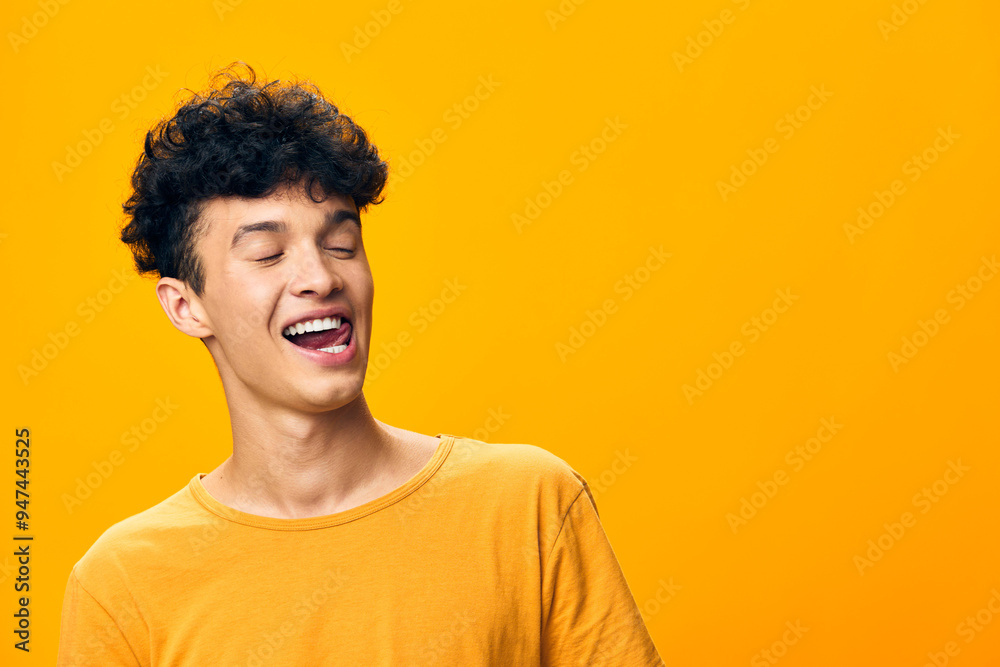 Young man with playful expression against bright yellow background, showcasing joy and positivity, wearing a casual yellow t shirt Smiling in a carefree manner Young man with playful expression against bright yellow background, showcasing joy and positivity, wearing a casual yellow t shirt Smiling in a carefree manner