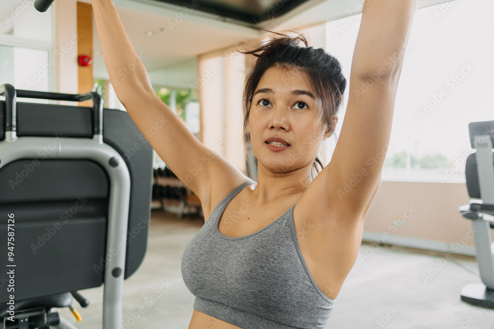 Fitness asian Thai woman using cable pull-down for back and arms exercise, get fit and firm at gym. Fitness asian Thai woman using cable pull-down for back and arms exercise, get fit and firm at gym.
