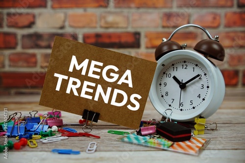 Mega Trends text on paper card with alarm clock and stationary on wooden background photo