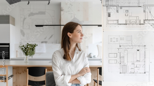 portrait of a woman designer in a office room and showing blueprints,