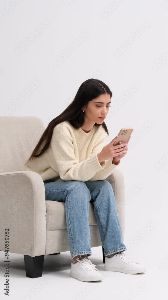 Serious Caucasian young adult woman using phone for messaging in internet on white background, spending leisure time with online entertainment. Vertical video.