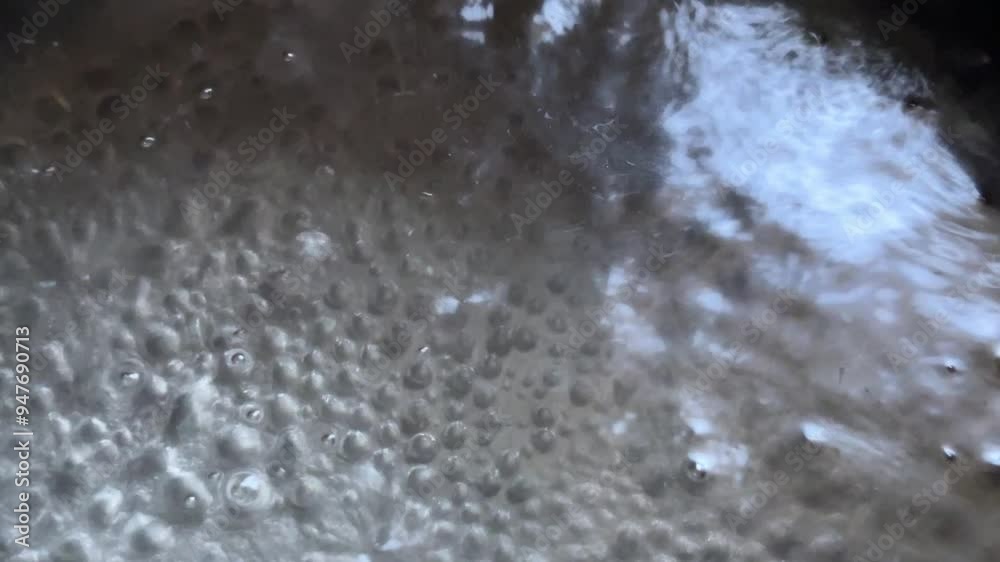 Water is boiling in a saucepan, contrast and shadows. The water is boiling. bubbles when water boils. Water is boiling in a saucepan, contrast and shadows. The water is boiling. bubbles when water boils.