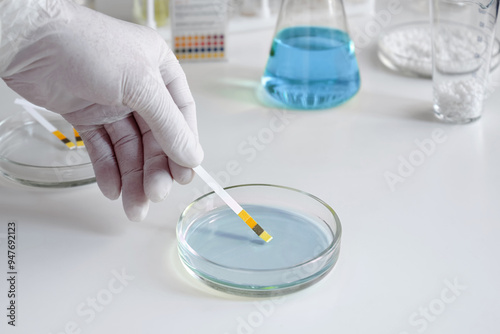 A scientist in a chemical laboratory takes measurements of the acid-base balance of a liquid in a Petri dish. photo