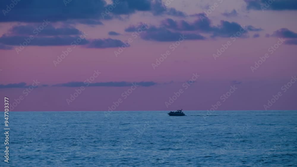 Beautiful evening colored sky, calm sea along which a small boat is sailing from right to left Beautiful evening colored sky, calm sea along which a small boat is sailing from right to left