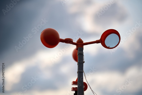 Tableau sur toile A red anemometer spins against a cloudy Hong Kong sky, measuring wind on a pole, blending technology with natural weather