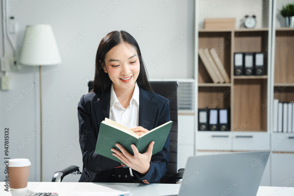 Business women talk mobile phones and take notes on their notebooks while working on laptop computers. Business women talk mobile phones and take notes on their notebooks while working on laptop computers.
