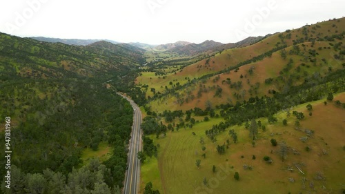 Aerial view of winding road through lush valley surrounded by serene hills and trees, Mendocino National Forest, California, United States.