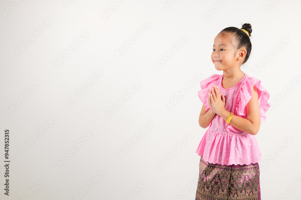 Portrait of Thailand kid girl smiling traditional Thai dress costume posing to pay respect in studio shot isolated white background, Happy kindergarten child sawasdee symbol or welcome Portrait of Thailand kid girl smiling traditional Thai dress costume posing to pay respect in studio shot isolated white background, Happy kindergarten child sawasdee symbol or welcome