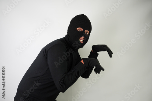 Young Adult black masked robber with gloves is running, fleeing and escaping. Concept for hacking, scamming, phishing.