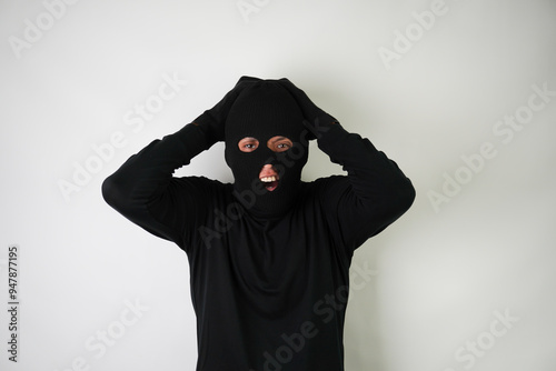 Shocked Young Adult black masked robber with gloves. Isolated over white background.