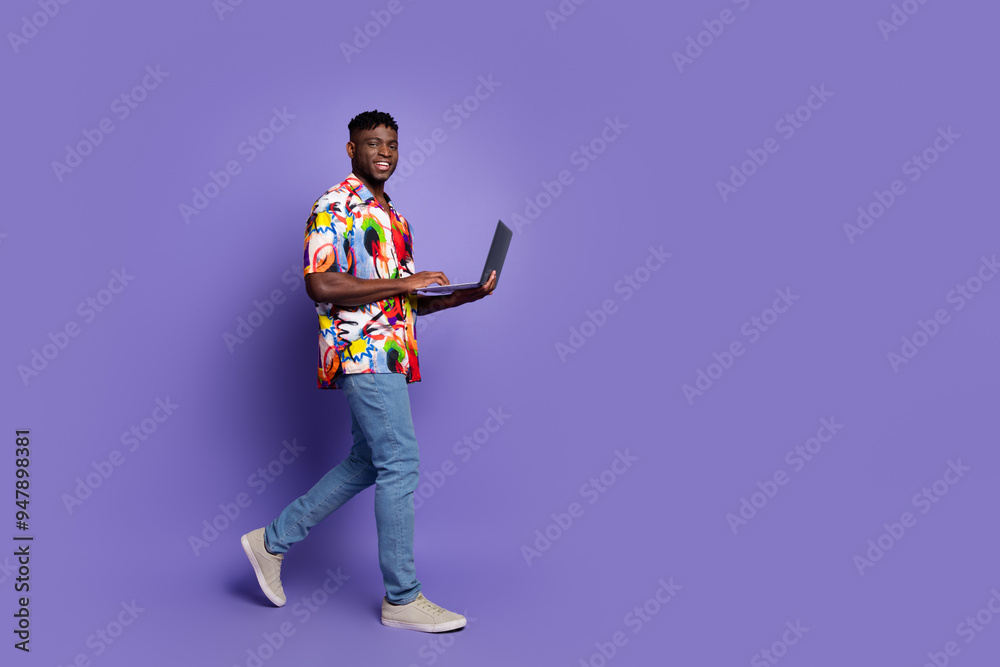 Full body photo of attractive young man netbook walking dressed stylish colorful clothes isolated on violet color background Full body photo of attractive young man netbook walking dressed stylish colorful clothes isolated on violet color background