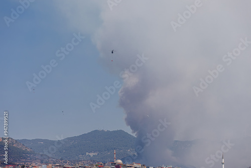Obraz na płótnie Turkey - Izmir 16 August 2024 Eurocopter AS532 Cougar type and Sikorsky helicopters carry the water they take from the sea to the fire area to intervene in the forest fire on Yamanlar Mountain. w salonie