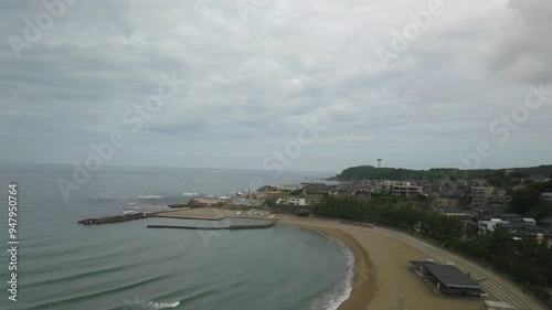 Aerial view of sandy beach and seaside village with buildings under a cloudy sky, Mikunicho Anto, Japan. photo