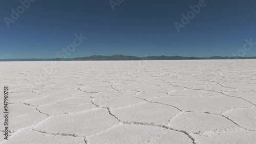 Aerial view from a drone advancing over the vast Salinas Grandes salt flats in Argentina, showcasing the expansive white surface and unique patterns of the salt lake. photo