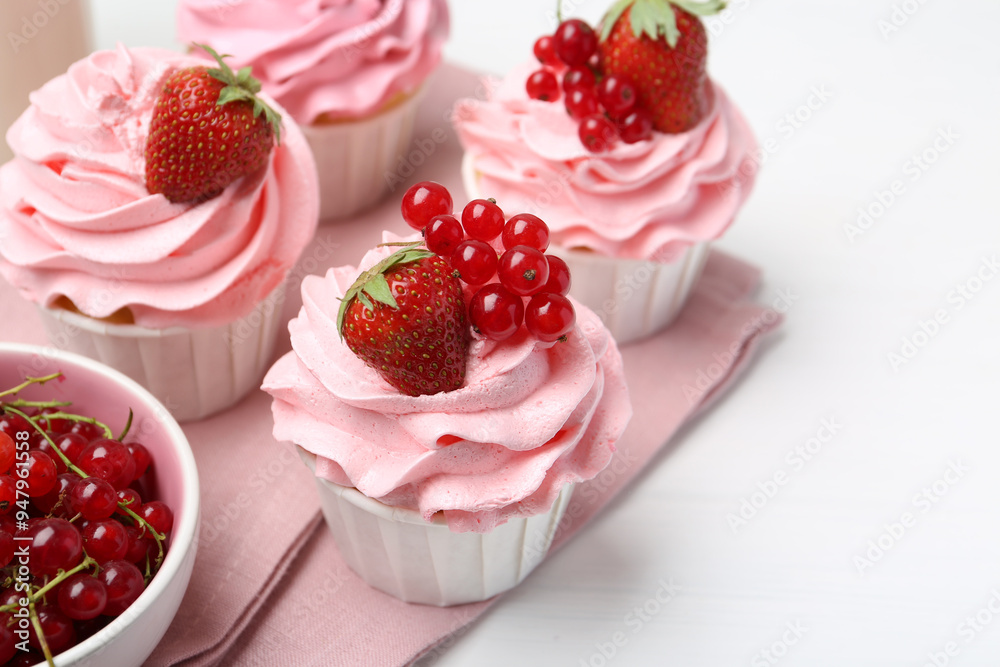 Tasty cupcakes with strawberries and red currants on white table, closeup. Space for text Tasty cupcakes with strawberries and red currants on white table, closeup. Space for text