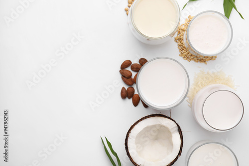 Different types of vegan milk and ingredients on white table, flat lay. Space for text