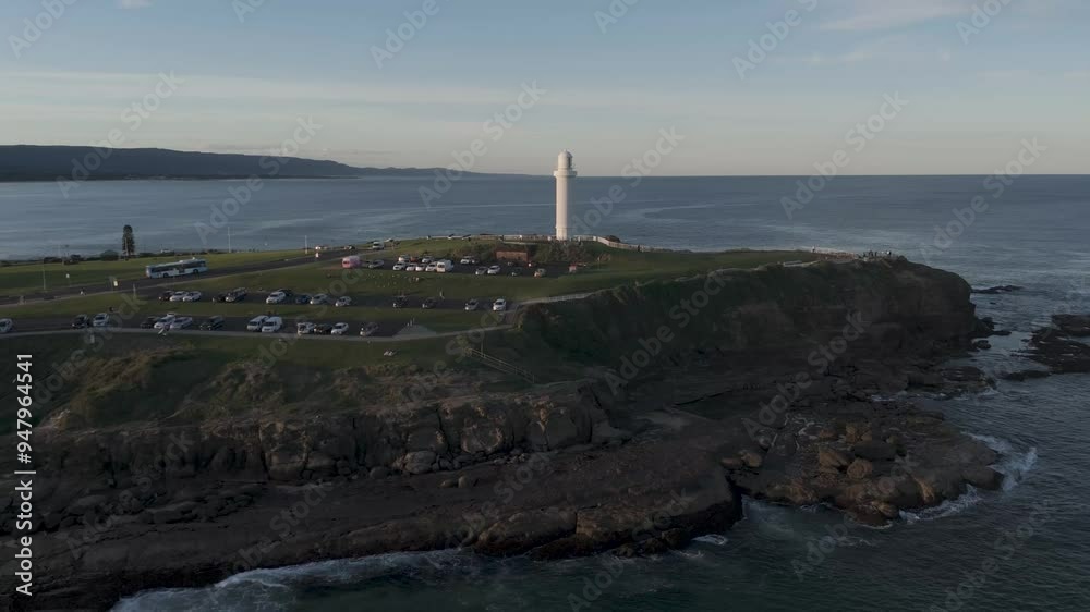 Aerial pullback from Wollongong sea tower, showcasing coastline and waves crashing onto the shore at dusk Aerial pullback from Wollongong sea tower, showcasing coastline and waves crashing onto the shore at dusk