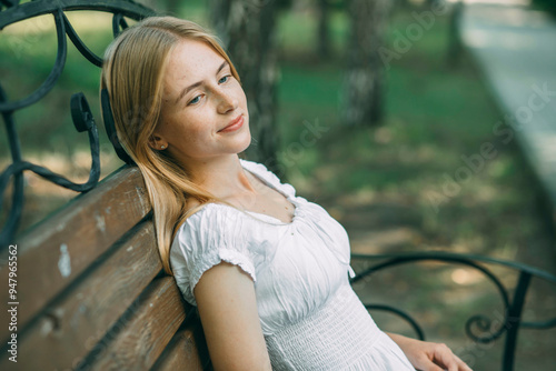 Obraz na plátně young woman with freckles enjoys a peaceful retreat on a park bench, away from the hustle and bustle of daily life