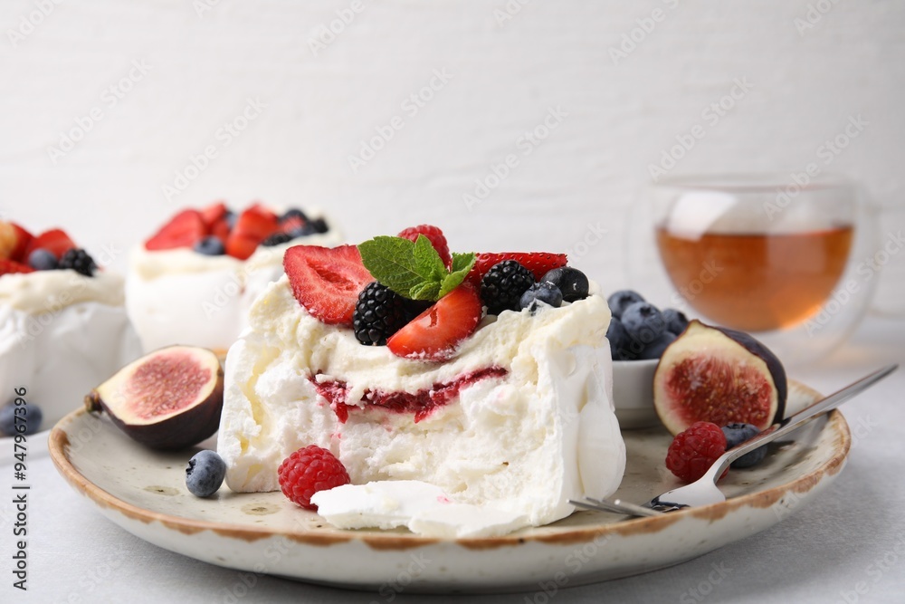 Pavlova cake (meringue dessert) with whipped cream, fresh berries, mint and fig on table, closeup Pavlova cake (meringue dessert) with whipped cream, fresh berries, mint and fig on table, closeup
