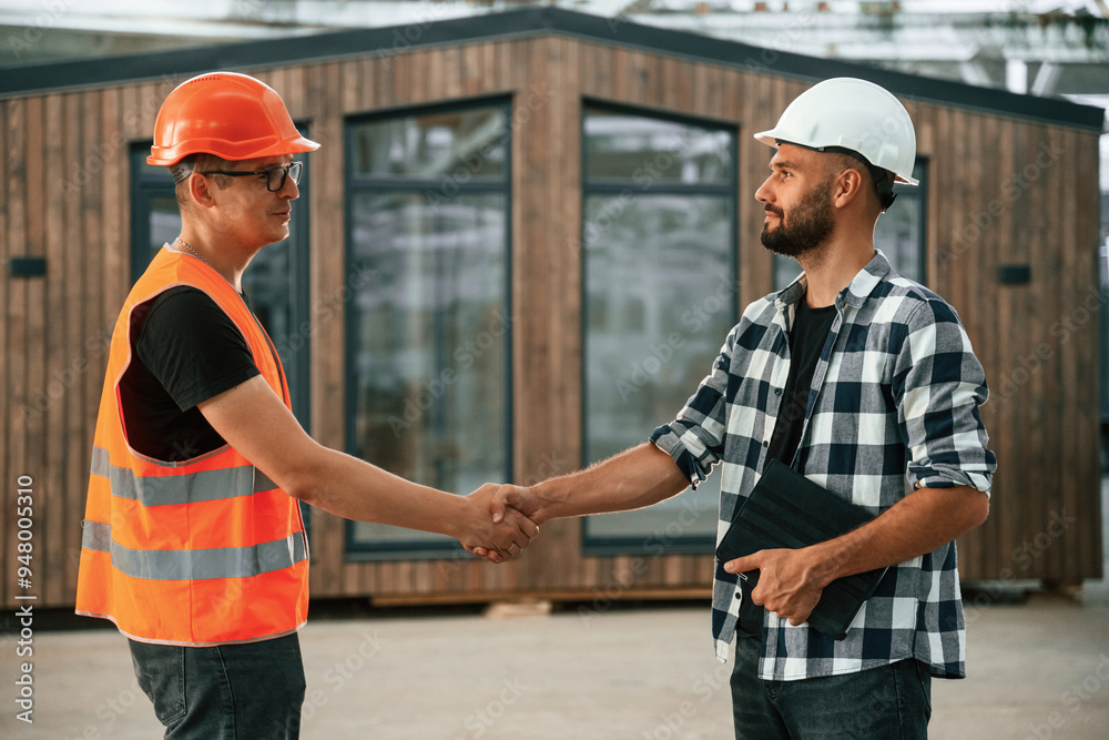 Agreement, handshake. Two workers are in the industrial wooden warehouse Agreement, handshake. Two workers are in the industrial wooden warehouse