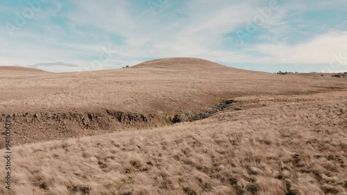 Sweeping aerial shot over plains of grass revealing water hole and creek system photo