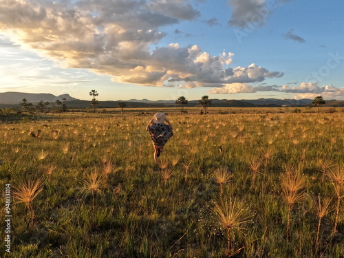 mulher caminhando em campo com palipalan (conhecidos como "chuveirinhos") na chapada dos veadeiros, goiás