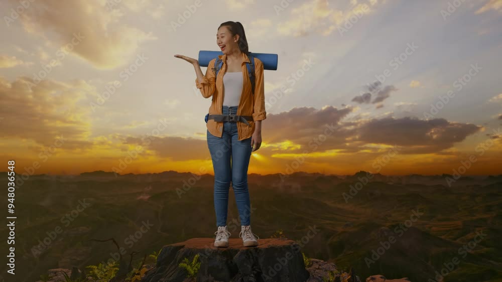 Full Body Of Asian Female Hiker With Mountaineering Backpack Smiling And Pointing To Side While Standing On The Top Of Mountain During Sunset Time