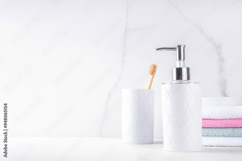 Bathroom shelf simple white background. Dispenser for soap, shower gel, soap dish, glass with toothbrushes, stack of towels on countertop. Mockup for cosmetics, body care products, copy space