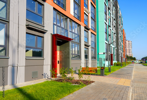 Entrance to a Eco-friendly residential building with green courtyard. Facade of New residential building with flats. Lawn at Condo house complex. Entrance to the staircase in apartment block. photo