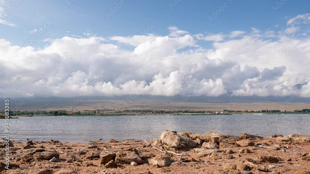 hyperlapse shot on the shore of Lake Issyk Kul, with an isoimage of the Tien Shan mountain range in the background, clouds moving over the mountains hyperlapse shot on the shore of Lake Issyk Kul, with an isoimage of the Tien Shan mountain range in the background, clouds moving over the mountains