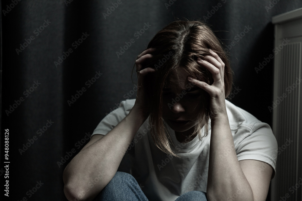 The woman in the photo looks depressed and scared, she has suffered from domestic violence or emotional abuse. Her posture is hunched, and her facial expression is anxious and sad The woman in the photo looks depressed and scared, she has suffered from domestic violence or emotional abuse. Her posture is hunched, and her facial expression is anxious and sad