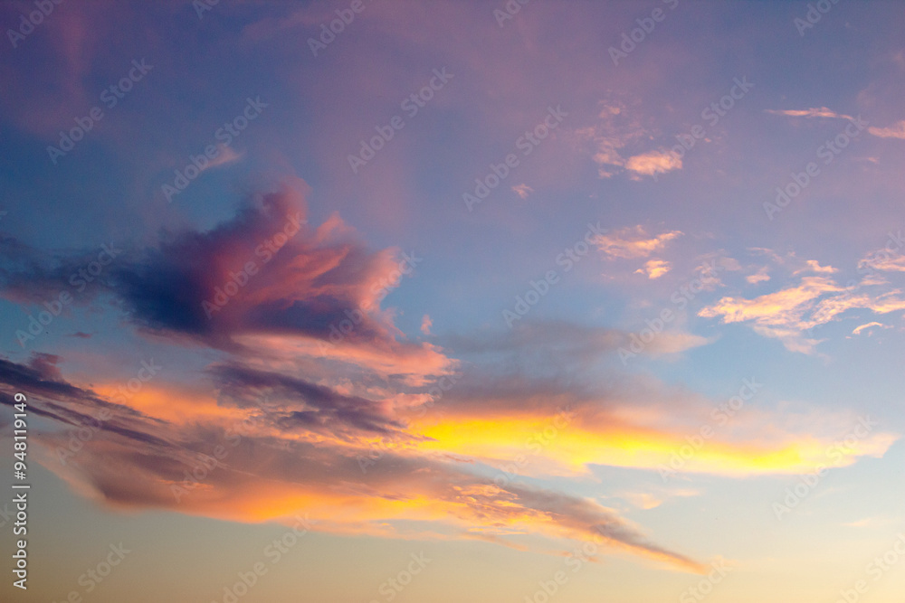 Fototapeta premium a peaceful post-sunset sky, painted in soft pastel shades of pink and purple, with wispy clouds gently illuminated by the fading sunlight, evoking a tranquil evening scene