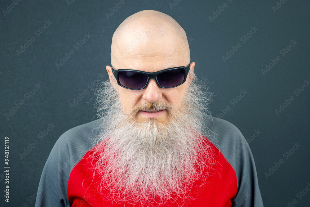 portrait of a successful bald man with a large gray beard wearing sunglasses on a dark gray background portrait of a successful bald man with a large gray beard wearing sunglasses on a dark gray background