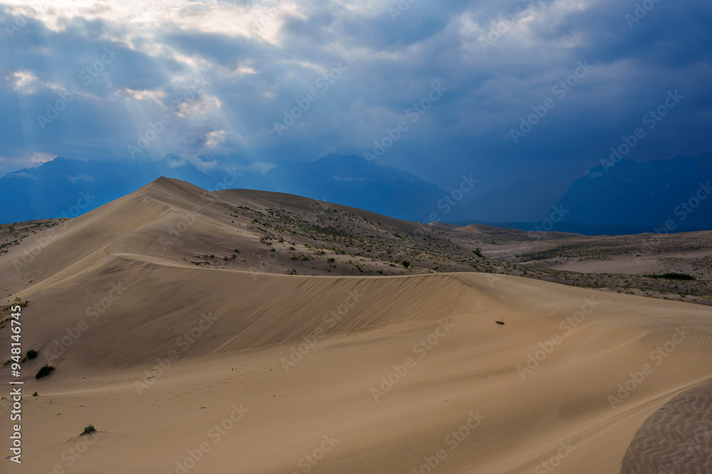 Dramatic desert dunes under sunbeams and cloudy sky Dramatic desert dunes under sunbeams and cloudy sky