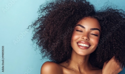 Afro woman with curly hair is smiling and looking at the camera