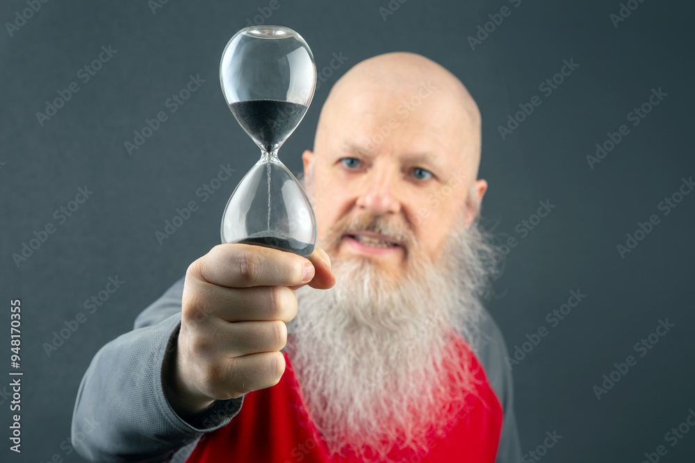bald man with a large white beard holds an hourglass in his hands. concept of fluidity of life time bald man with a large white beard holds an hourglass in his hands. concept of fluidity of life time