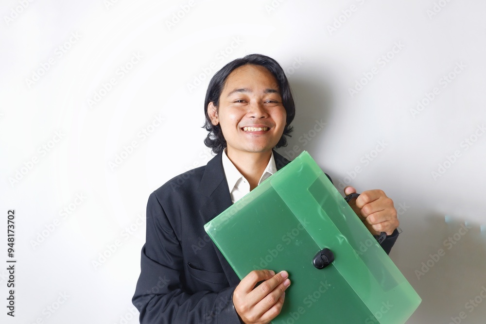 a young Indonesian man with long hair wearing a black suit carries documents required for work on an isolated white background a young Indonesian man with long hair wearing a black suit carries documents required for work on an isolated white background