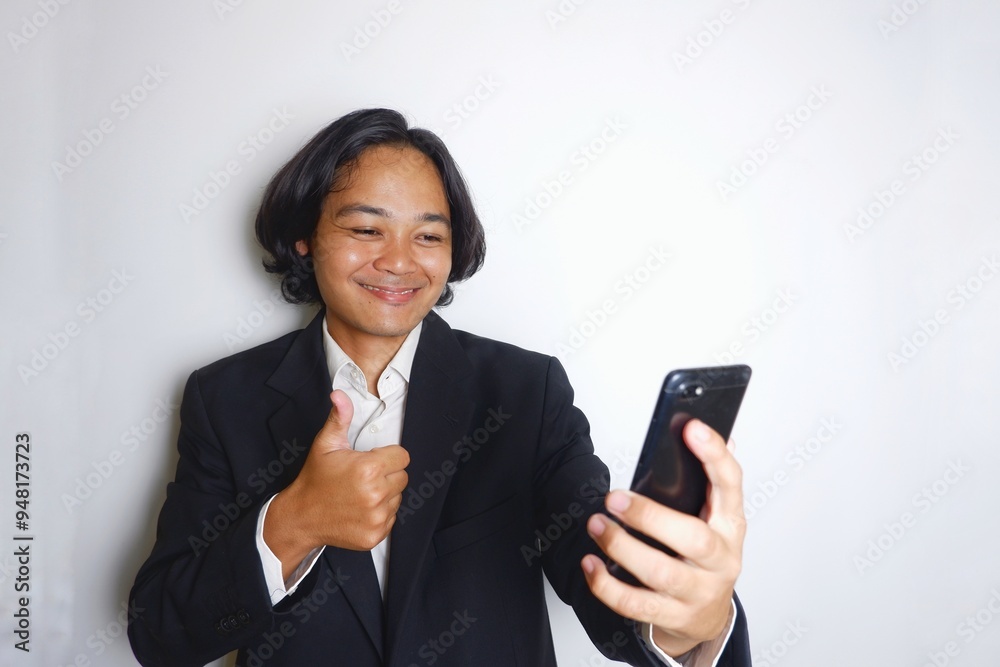 a young Indonesian man with long hair wearing a black suit carries documents required for work on an isolated white background a young Indonesian man with long hair wearing a black suit carries documents required for work on an isolated white background