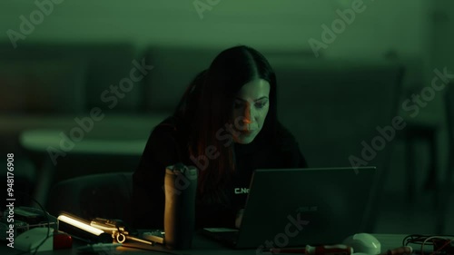 A beautiful young female programmer is enthusiastically working on a laptop. Girl hacker typing at the computer. 