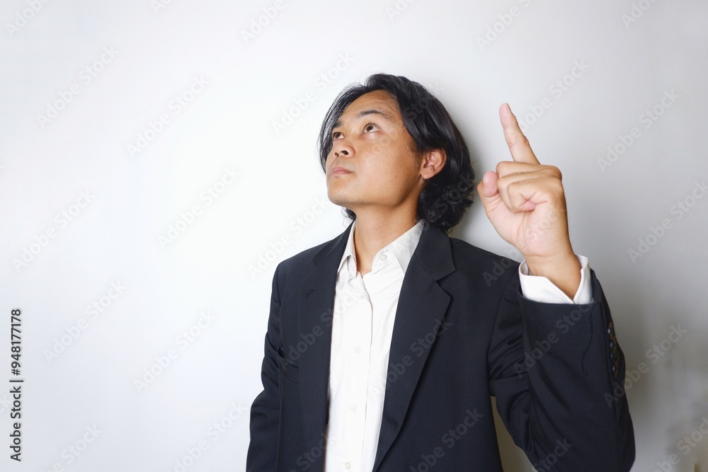 a young Indonesian man with long hair wearing a black suit carries documents required for work on an isolated white background a young Indonesian man with long hair wearing a black suit carries documents required for work on an isolated white background