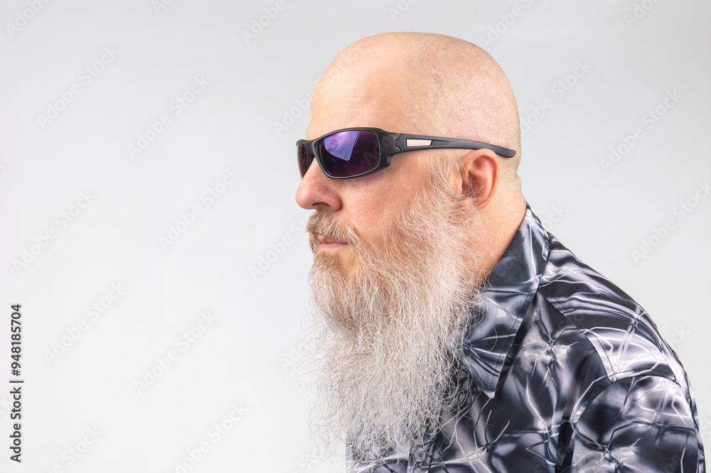 portrait of a successful bald man with a large gray beard wearing sunglasses on a light background. portrait of a successful bald man with a large gray beard wearing sunglasses on a light background.